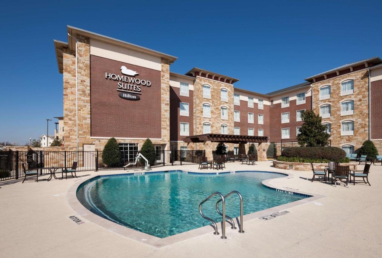 Outdoor hotel pool area with lounge chairs and blue sky