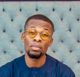 Man in blue shirt and yellow-tinted glasses looking serious